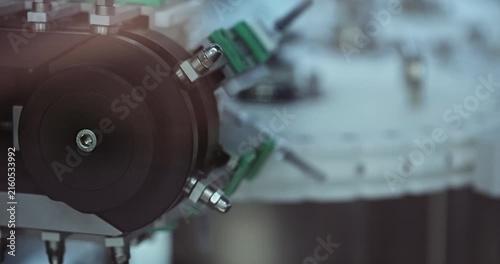Small glass vials with pharmacy transported by rotating production system at factory. High-capacity manufacturing supports medical packaging operations
