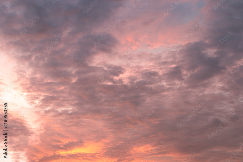 Fototapeta premium At sunrise or sunset, clouds—streaked with various hues like orange and reddish-yellow—lend a dramatic quality to the sky.