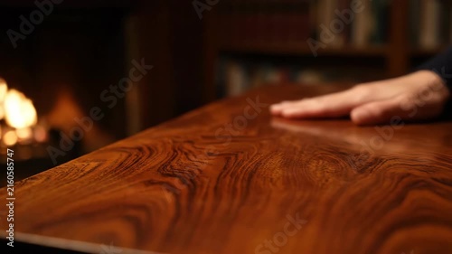 Close up of hands resting on polished wooden table in warm room