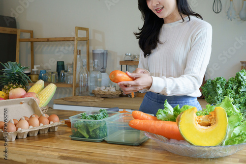Young Asian Woman Preparing Fresh Vegetables in Kitchen for Healthy Nutrition and Clean Eating Lifestyle surrounded by kale, pumpkin, and fresh vegetables, healthy eating and nutrition