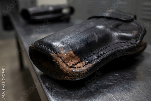 Macro close up of the corner of a professional black leather gun holster showing slight friction wear