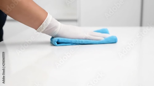Close up of gloved hands wiping a clean table with disinfecting cloth