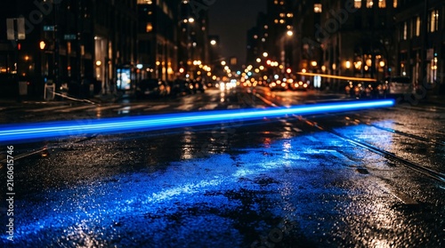 Cobalt light streak illuminates wet asphalt at night in a city street