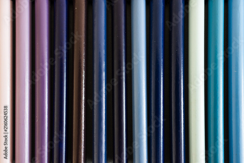 close-up of violet purple and blue colored pencils neatly lined up in pencil case, concept of creativity, drawing, education and art supplies