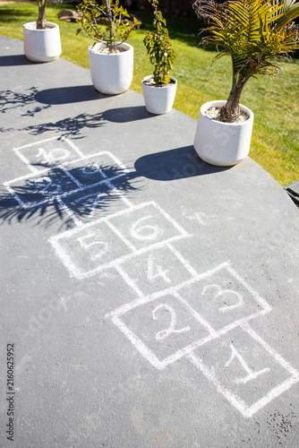 chalk hopscotch game drawn on concrete patio in australian backyard