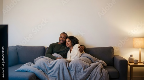 Happy couple sitting on sofa watching television in living room at night