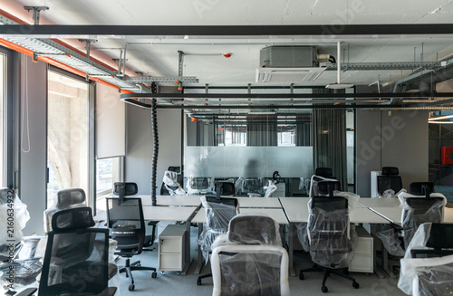 Fotografía Modern Open-Plan Office Under Renovation with Plastic-Wrapped Chairs and Exposed