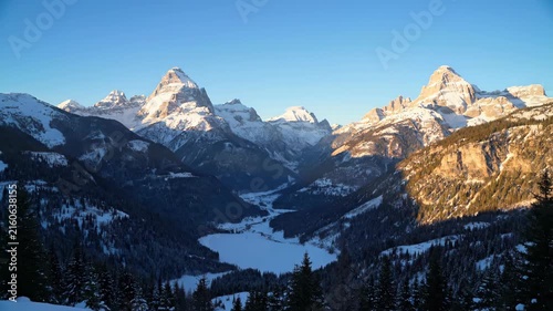 Snowy mountain valley at golden sunrise with clear blue sky