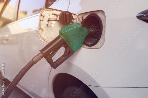 A close-up image of a gas station attendant's hand holding a fuel dispenser.	