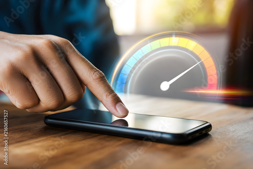 Hand touching smartphone with virtual colorful speedometer gauge displaying performance rating and efficiency level