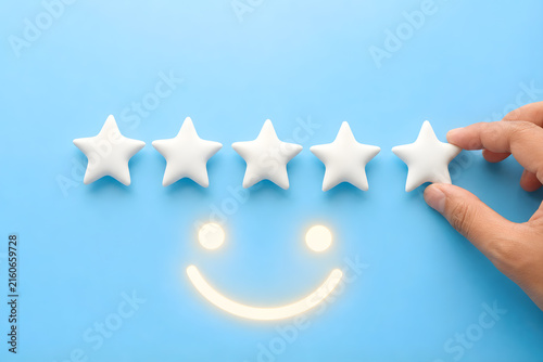 Hand placing fifth star to complete a five-star rating with glowing smiley face on blue background