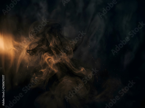 Dramatic black smoke swirling with glowing amber light in dark abstract background