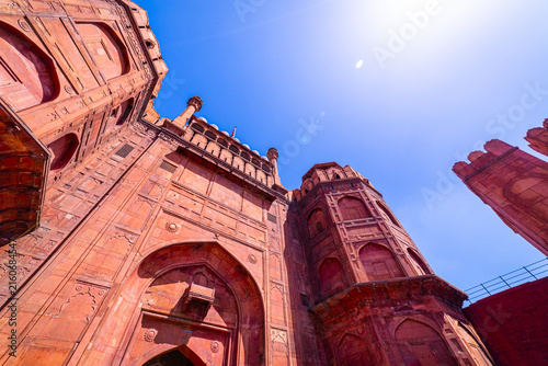 Fotografie Low-angle view of monumental sandstone gateways and walls inside the Red Fort in Delhi, India, emphasizing the grandeur of Mughal architecture under bright sunlight