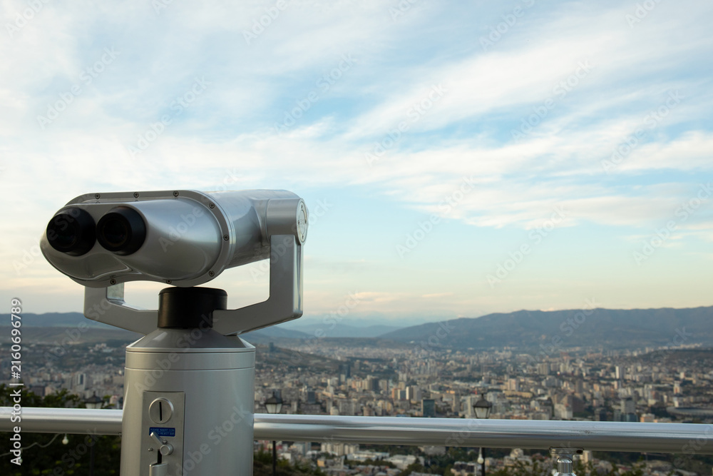 Naklejka premium City skyline viewed through binoculars from elevated viewpoint
