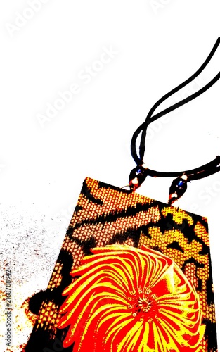 Close-up of a unique handmade ethnic necklace featuring a patterned fabric pendant with a vibrant orange floral design on a black cord. Perfect for fashion, crafts, and cultural accessories.