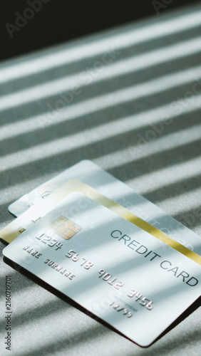 Cashless payment methods, silver and golden credit cards on table under Venetian blind shadow. payment online concept.