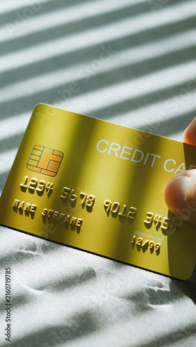 Financial privacy, hand touching gold credit card under Venetian blinds light and shadow. Personal secure Banking concept.