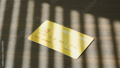 Cashless society, modern credit card on dark table with soft window blind shadow.