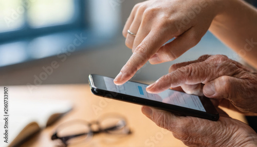 Elderly hand younger hand smartphone mobile phone technology help support guidance touchscreen learning intergenerational connection family senior adult finger contact communication internet