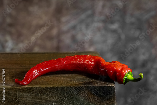 Red chili pepper with water drops on wood