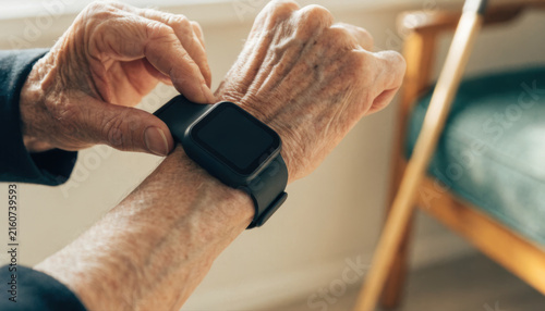 Senior hand smartwatch elderly wrist device aging skin closeup health technology modern wearable wooden cane home interior monitoring concept lifestyle independence