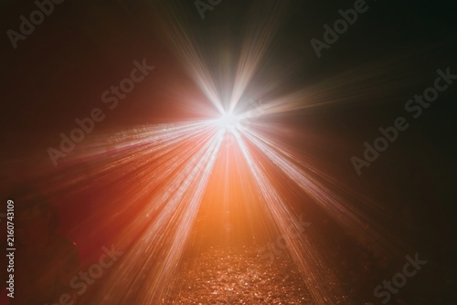 Radiant yellow and purple light beams bursting from a central point against a deep orange background, glowing and electric for design overlays