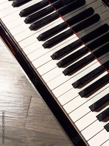 Cuadro en lienzo Vertical close-up of piano keys with copy space on wooden floor background for music education, concert, and art concepts