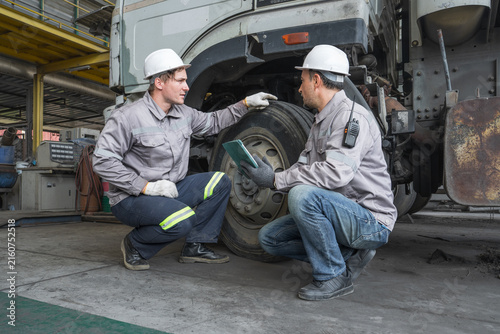 Two mechanics inspecting truck tire condition during maintenance services.