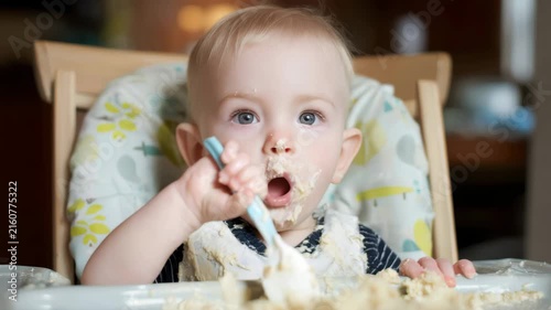 Baby boy enjoying messy self-feeding mealtime in high chair