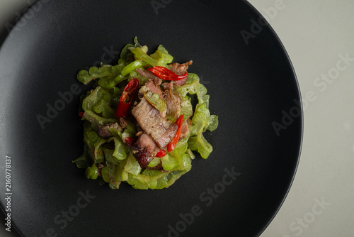 Konstfotografi Top-down close-up view of stir-fried bitter melon with tender roasted pork slices and red peppers served on a dark plate