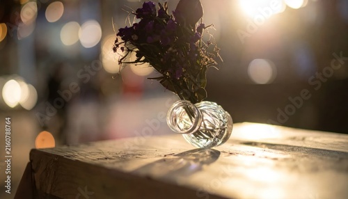 Glass vase with dried flowers on a wooden table.