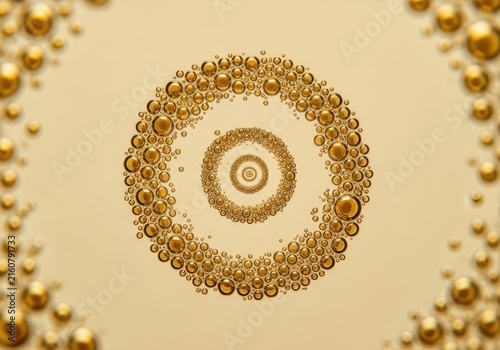 Golden bubbles forming concentric circles and abstract patterns against a soft yellow background