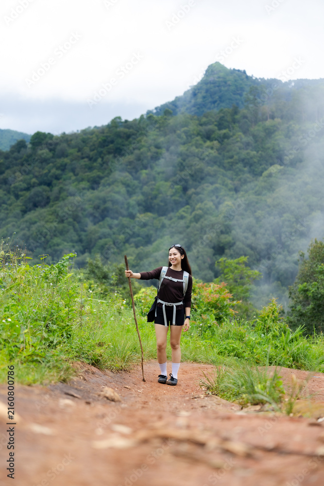 Fototapeta premium Mountain hiker female traveler forest trail misty mountain green forest hiking woman enjoys scenic nature adventure rugged path surrounded by lush vegetation, woodland, and misty mountain landscape
