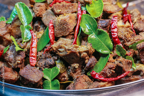 Quadro su tela Close up of tender braised beef stir fried with kaffir lime leaves and dried chilies in a pan, offering an authentic spicy Thai culinary visual for restaurant menus and food blogs