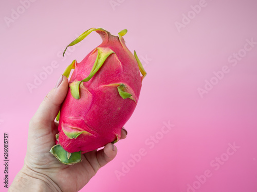 Konstfotografi Exotic red dragon fruit held in hand on a vibrant pink background