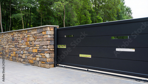 Принти на полотні Elegant black sliding entrance gate with decorative cutouts and stone pillar ent