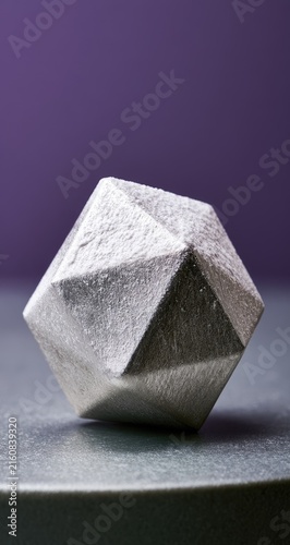 Geometric, crystalline, faceted object resting on a textured surface