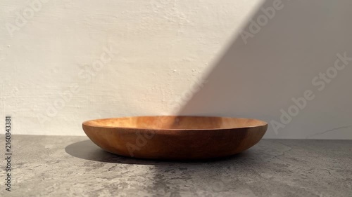 side view of empty wooden plate with shadows. gray cement table. white wall. copy space, empty, free, negative, text, design. black, dark. line, lines. sunlight, sunrise, sunshine. product. close up. 