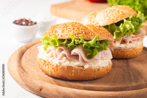 Sesame bagel sandwiches with turkey and chicken ham, cream cheese and fresh lettuce. Healthy food bun burger concept.