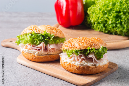 Sesame bagel sandwiches with turkey and chicken ham, cream cheese and fresh lettuce. Healthy food bun burger concept.
