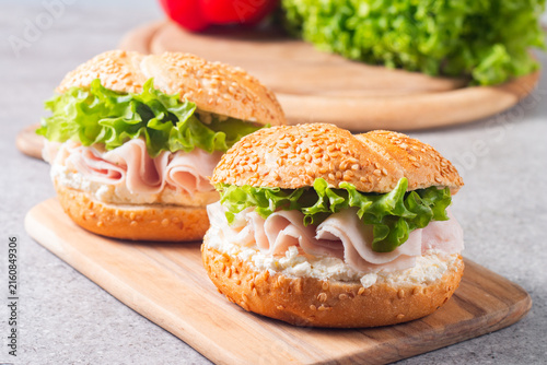 Sesame bagel sandwiches with turkey and chicken ham, cream cheese and fresh lettuce. Healthy food bun burger concept.