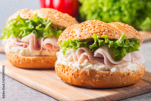 Sesame bagel sandwiches with turkey and chicken ham, cream cheese and fresh lettuce. Healthy food bun burger concept.