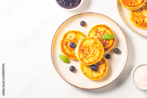 Golden cottage cheese pancakes with sour cream, blueberry jam and fresh berries. Healthy breakfast concept.