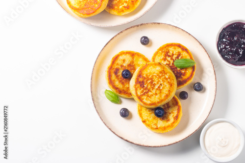 Golden cottage cheese pancakes with sour cream, blueberry jam and fresh berries. Healthy breakfast concept.