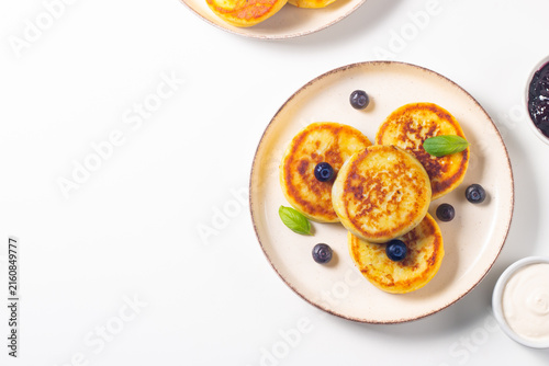Golden cottage cheese pancakes with sour cream, blueberry jam and fresh berries. Healthy breakfast concept.