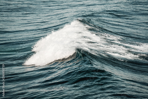 Close-up photograph of choppy ocean waves with white foam and textured teal-blue water surface