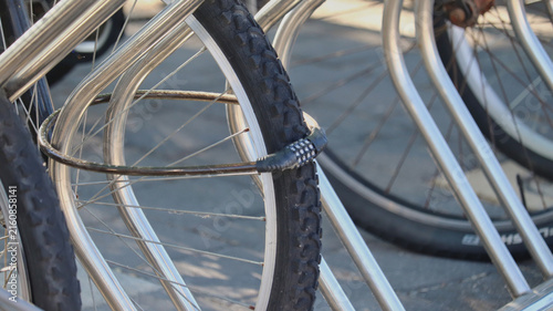 Картината върху платно Bicycle Wheel Secured with Combination Lock to Metal Bike Rack in Urban Setting