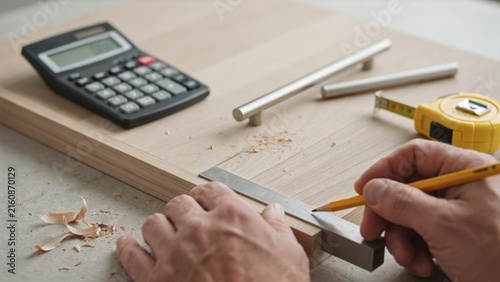 Photography Carpenter precisely marking measurements on wooden board using metal ruler with