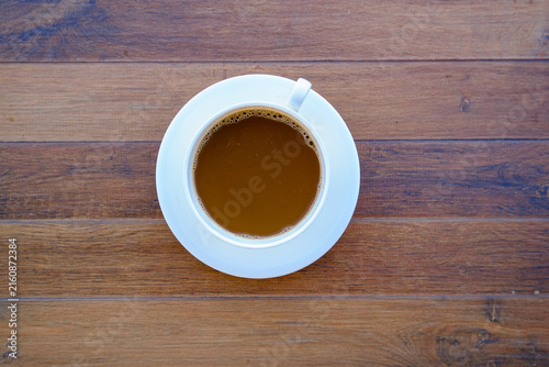 Canvastavla Aroma of Morning Brew: A white ceramic cup, filled with rich, dark coffee, rests on a rustic wooden table, inviting a moment of quiet contemplation and warmth