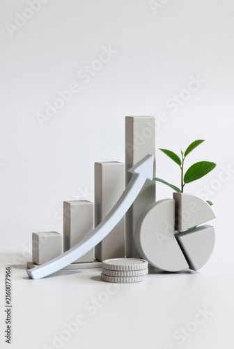 Abstract financial growth concept featuring gray bar graphs, a pie chart, coins, and a green plant symbolizing sustainability and economic progress